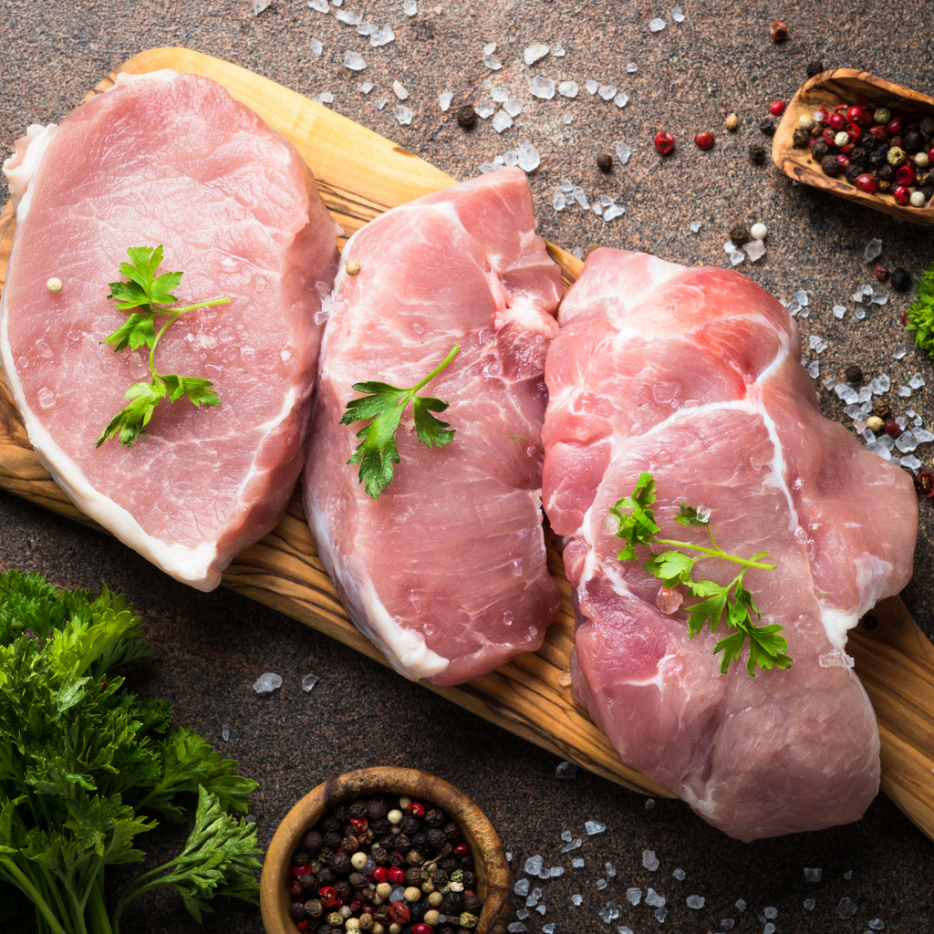 selection of pork chops on a chopping board with herbs